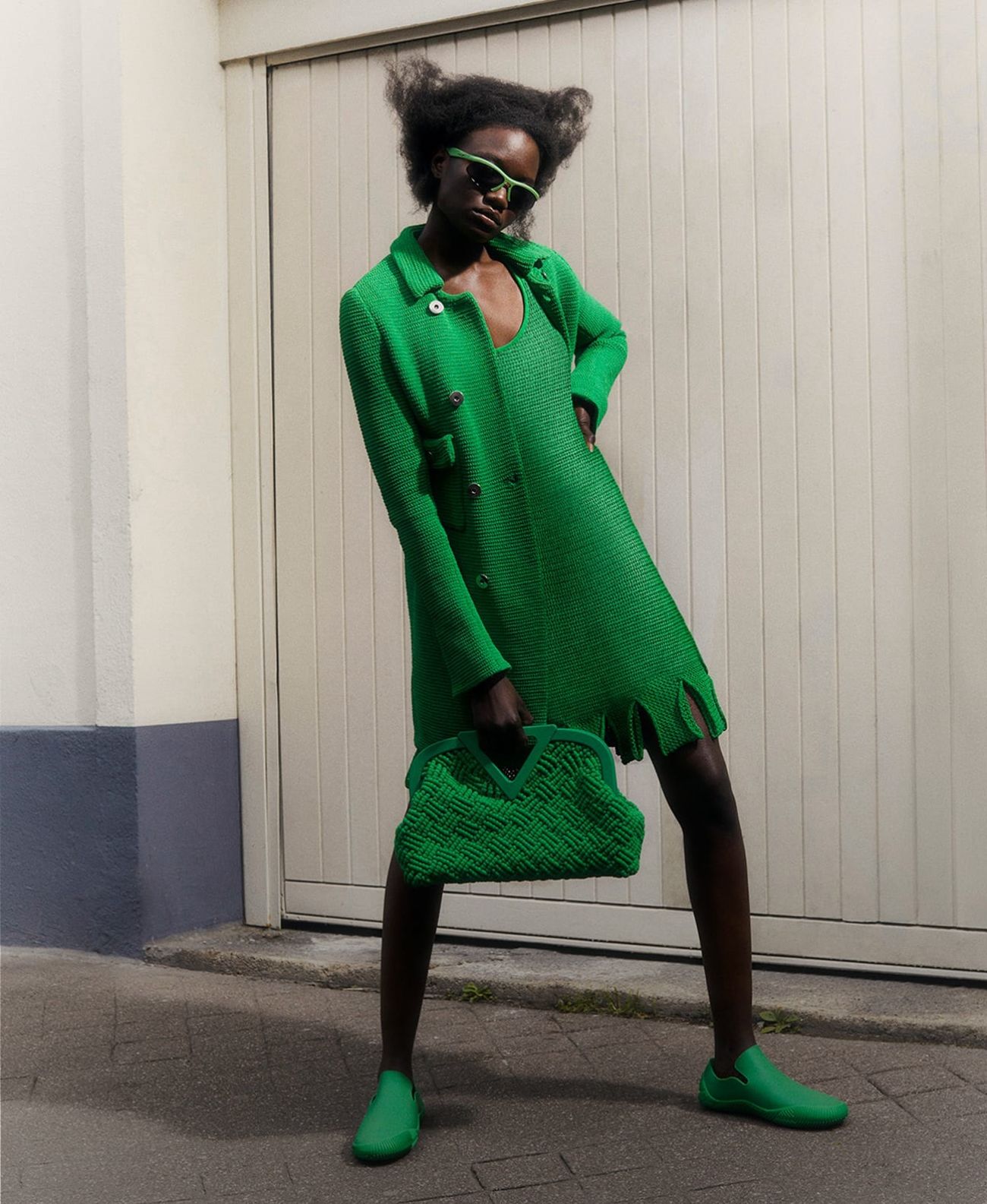 The Power Players: Mary N'Diaye by Antoine Harinthe for Matches Fashion Spring-Summer 2021 Ad Campaign. Clothing: Bottega Veneta Green Double-breasted cotton-blend knitted coat / Bottega Veneta Green Looped-hem scoop-neck cotton-blend mini dress / Bottega Veneta Green Point cotton-macramé clutch bag / Shoes / sunglasses by Bottega Veneta