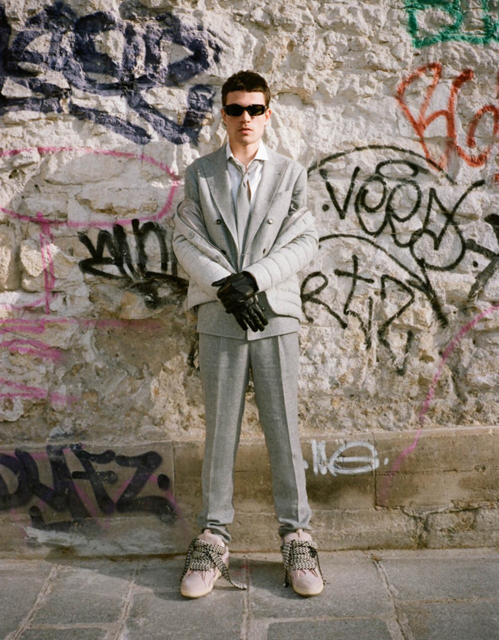 Clothing & Accessories: Herno padded button-up jacket / Jacket, Trousers, Shirt, Tie by Brunello Cucinelli / Sneakers by Lanvin / Sunglasses by Gentle Monster / Photographer: Pierre-Ange Carlotti. Stylist: Marc Goehring. Hair Stylist: Yoann Fernandez