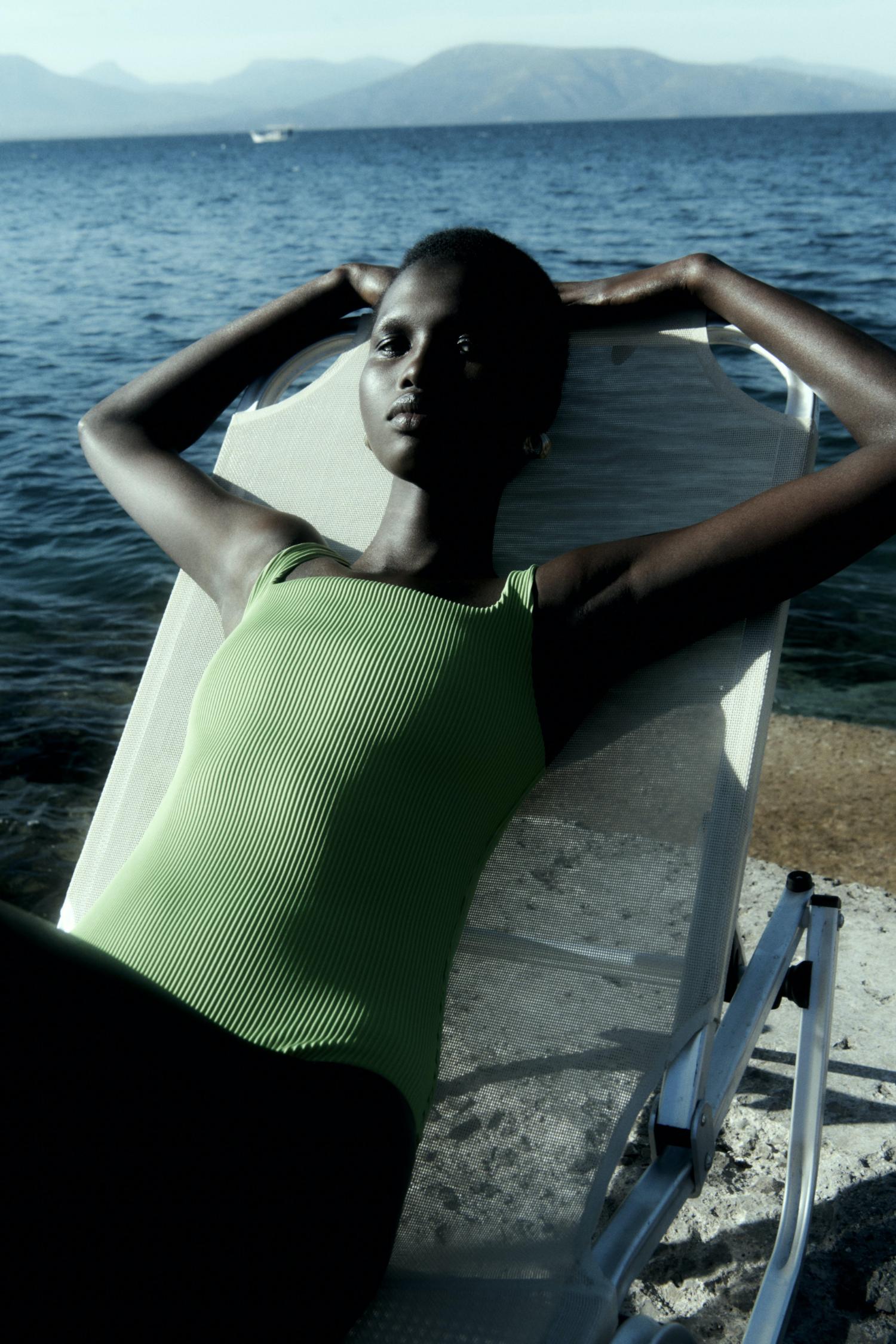 Amar Akway by Robin Galiegue for COS Summer 2021 Ad Campaign. Clothing: COS BRIGHT GREEN OPEN-BACK SWIMSUIT / COS GOLD TEXTURED HOOP EARRINGS