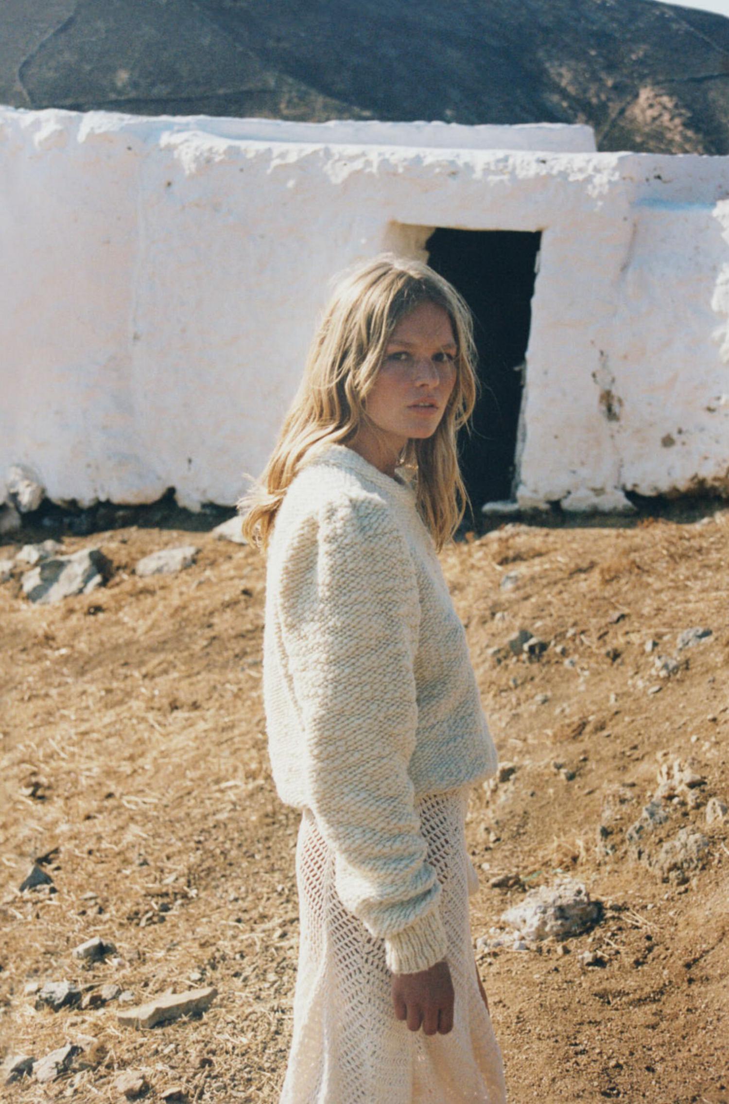 Anna Ewers in Mykonos by Henrik Purienne for Vogue Paris August 2021. Clothing: Sweater by Isabel Marant; Skirt by Akoia Swim; Makeup using Dior Beauty