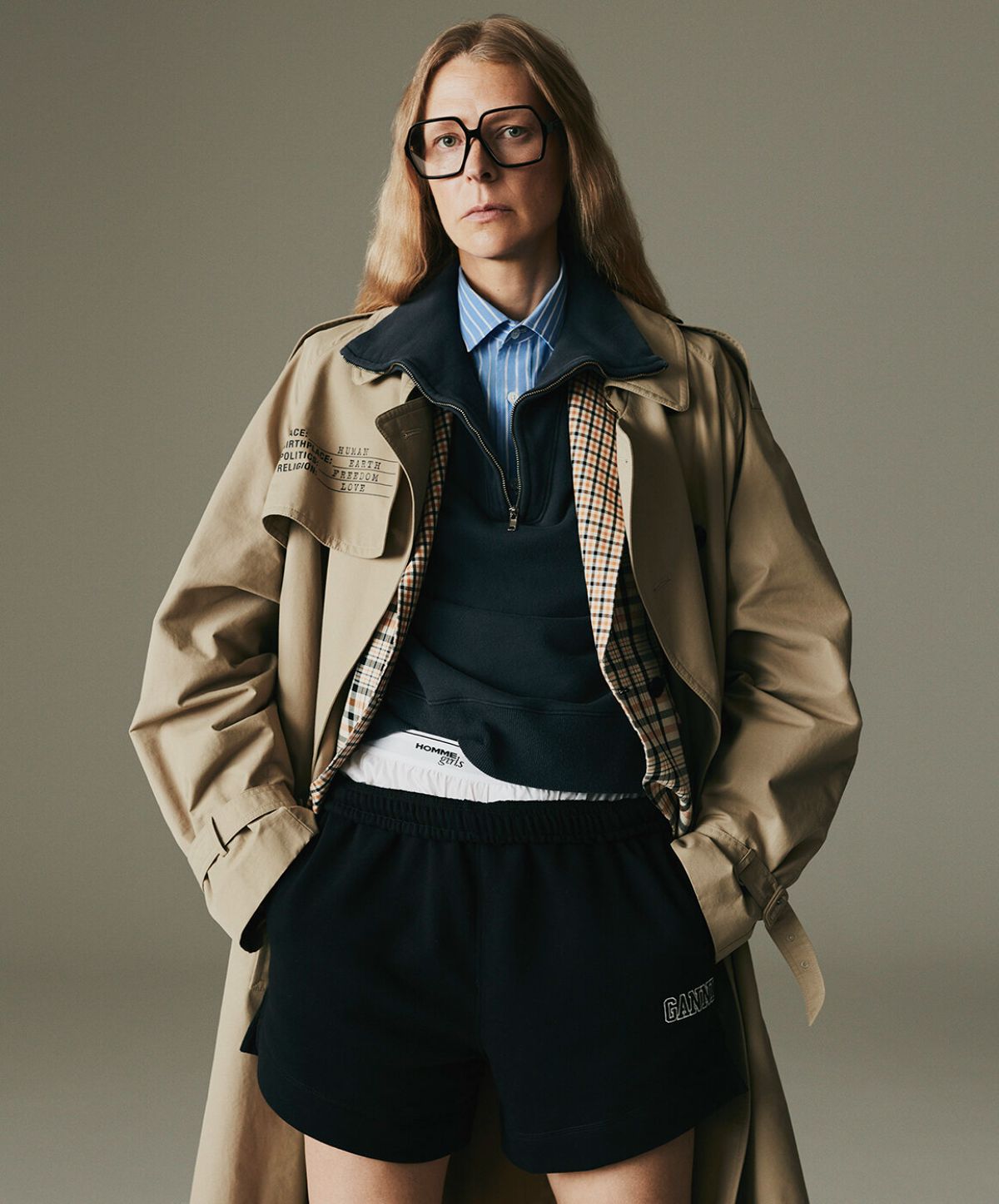 Hybrid Dressing: Laura Morgan by Sarah Piantadosi for Matches Fashion Fall-Winter 2021 Ad Campaign. Clothing & Accessories: Vetements Neutral Human Identity belted cotton-blend trench coat / Another Tomorrow White Single-breasted organic-cotton blend jacket / HommeGirls Blue Cropped striped cotton-poplin shirt / HommeGirls White Logo-waistband cotton pyjama shorts / Ganni Navy Software organic cotton-blend track shorts / Celine Eyewear Black Oversized square acetate glasses