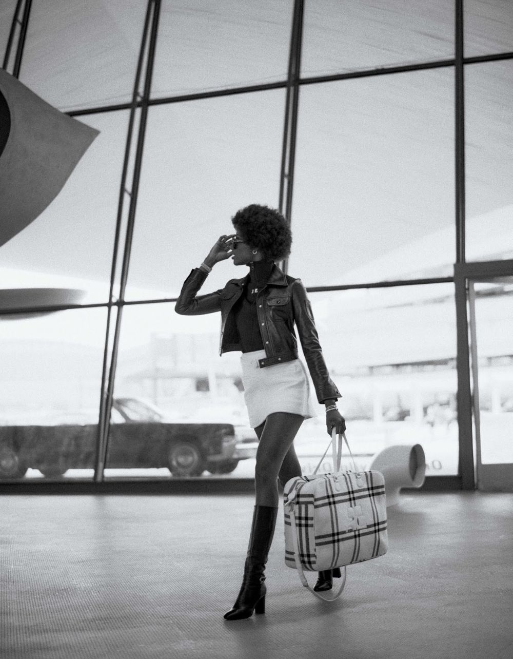 Express Lane: Mayowa Nicholas by Chris Colls for Elle Magazine September 2021. Clothing & Accessories: Jacket, vest, skirt, belt, tote by Courreges / Gianvito Rossi Black Hynde 85 leather knee-high boots / Sunglasses by Dior / Earrings, bracelets by Tiffany & Co.; Watch by Rolex