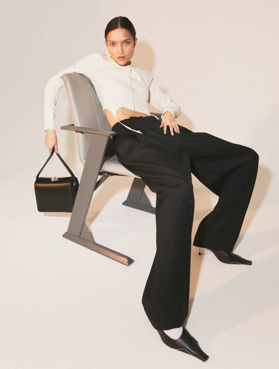 Charlotte Carey by Mattias Bjorklund for Elle Sweden January 2022 Clothing & Accessories: White La Chemise Draio cropped shirt by Jacquemus / Trousers by COS / Socks by COS / Bag by Susan Szatmary / Black Pointed Bavotte Heels by Acne Studios / Earrings by Acne Studios 