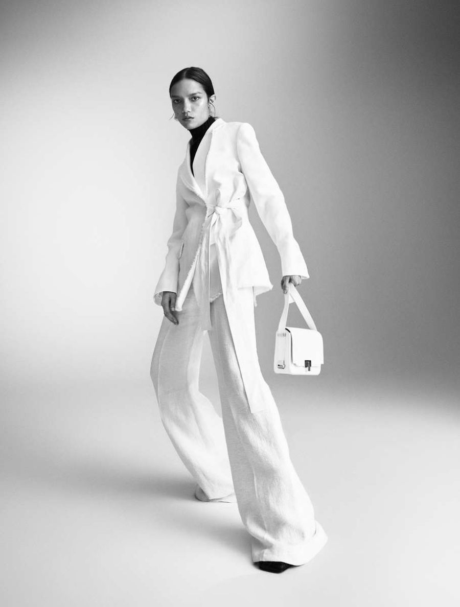 Charlotte Carey by Mattias Bjorklund for Elle Sweden January 2022 Clothing & Accessories: White Pleated linen wide-leg pants by Chloe / Jacket by Chloe / Polo by A. Roege Hove / Black Leather ankle boots by Acne Studios / Earrings by Acne Studios / Bag by Susan Szatmary. Earring by Maria Nilsdotter