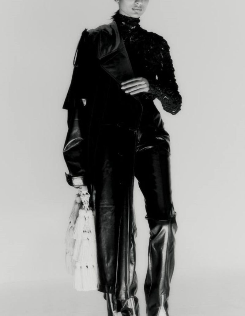 Chawntell Kulkarni by Umit Savaci for How to Spend It Magazine November 2021 Clothing & Accessories: Bottega Veneta stretch macrame trench coat, macrame top, stretch-latex trousers, ankle boots, and leather Tassel bag.