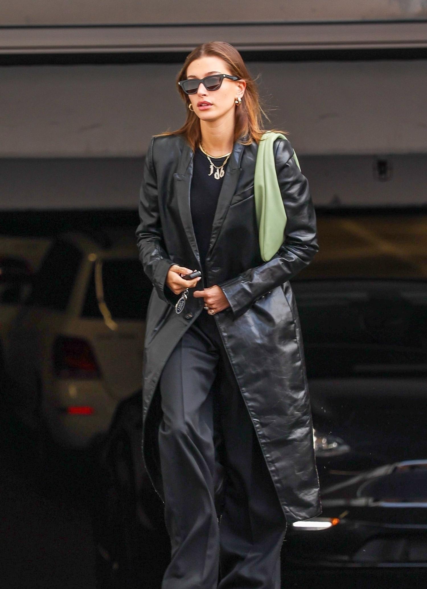 Hailey Bieber in Black Leather Coat, Balenciaga Black Wide-Leg Trousers, Olive Green Shoulder Bag Outfit