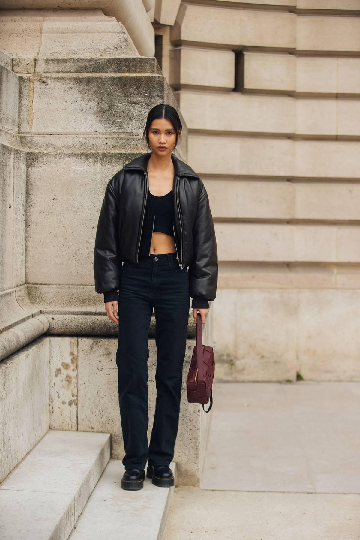 Jinrong Huang wears Acne Studios Zip Puffer Jacket and Bottega Veneta Burgundy Brick Cassette Bag at Paris Fashion Week Fall-Winter 2023