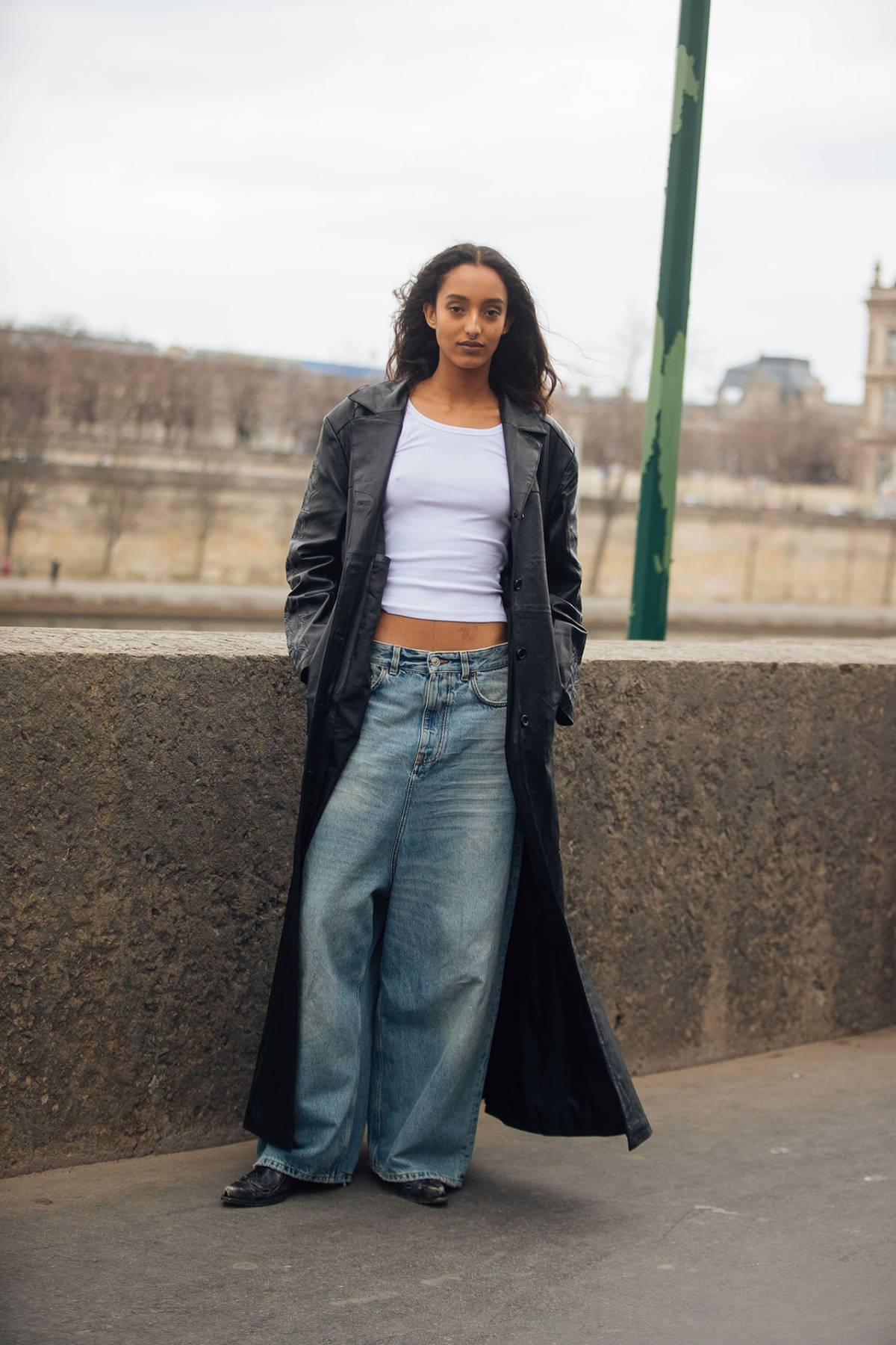 Mona Tougaard wears Black Leather Coat with Blue Baggy Jeans and White Tank Top at Paris Fashion Week Fall-Winter 2023
