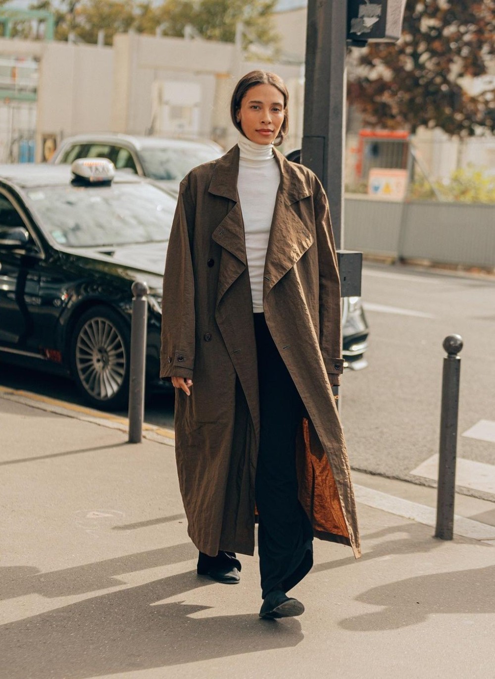 TyLynn Nguyen in Lemaire Brown Trench Coat, REFINE White Turtleneck, The Row Black Sock Loafers at Paris Fashion Week Spring-Summer 2023