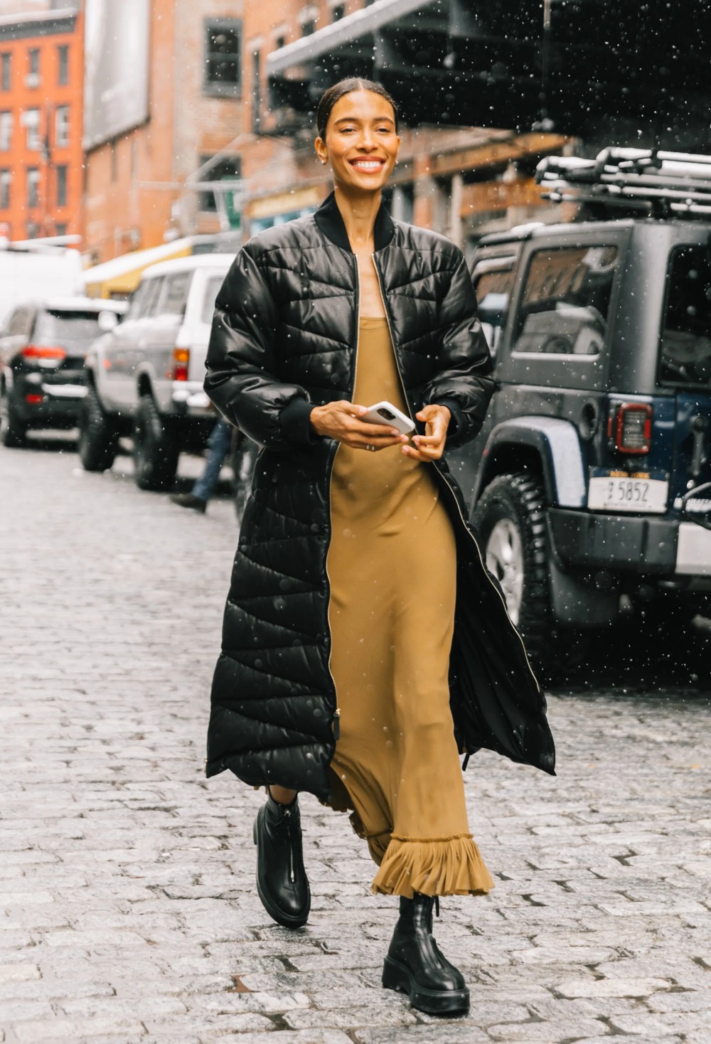 Tylynn Nguyen wears Black Longline Puffer Coat, Khaite Dress, The Row Boots at New York Fashion Week