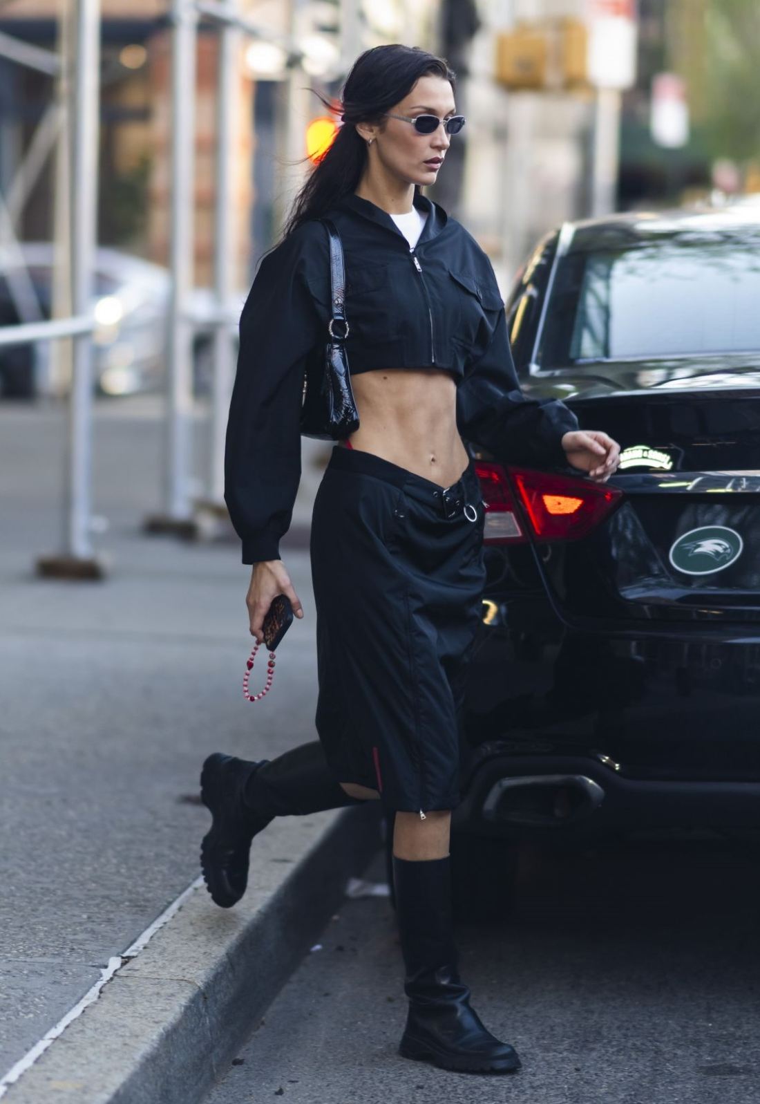 Bella Hadid in New York wearing Black Cropped Jacket, Nylon Cargo Skirt, 90s Style Black Shoulder Bag, and Vintage Prada Tall Boots Outfit