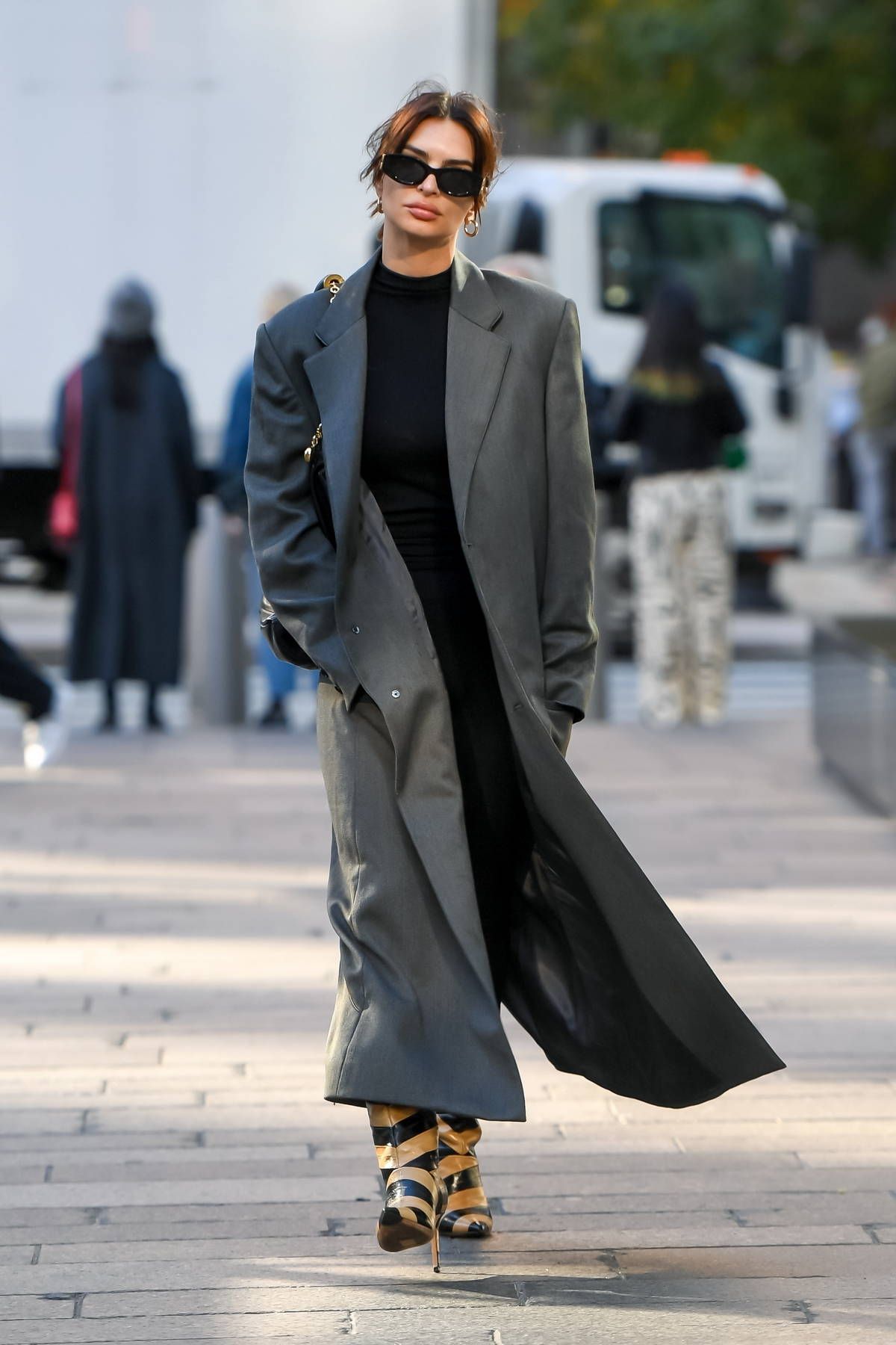 Emily Ratajkowski in New York City wearing Mimchik Grey Coat, Loewe Black Squeeze Bag, Miu Miu Miu Glimpse Sunglasses, Jimmy Choo Beren Boots